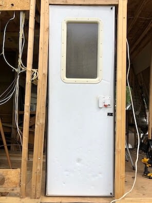 light gray door inside wooden frame that is not square